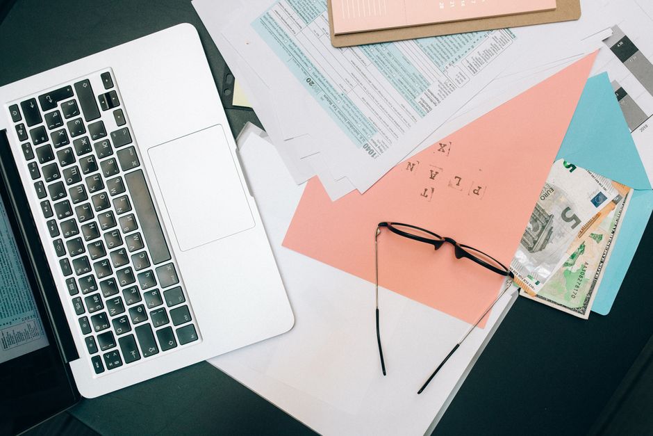 Laptop, rental property documents and eyeglasses on a desk