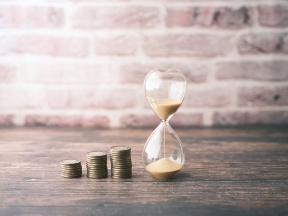 Hourglass beside stacked coins, representing the daily cost of holding a property