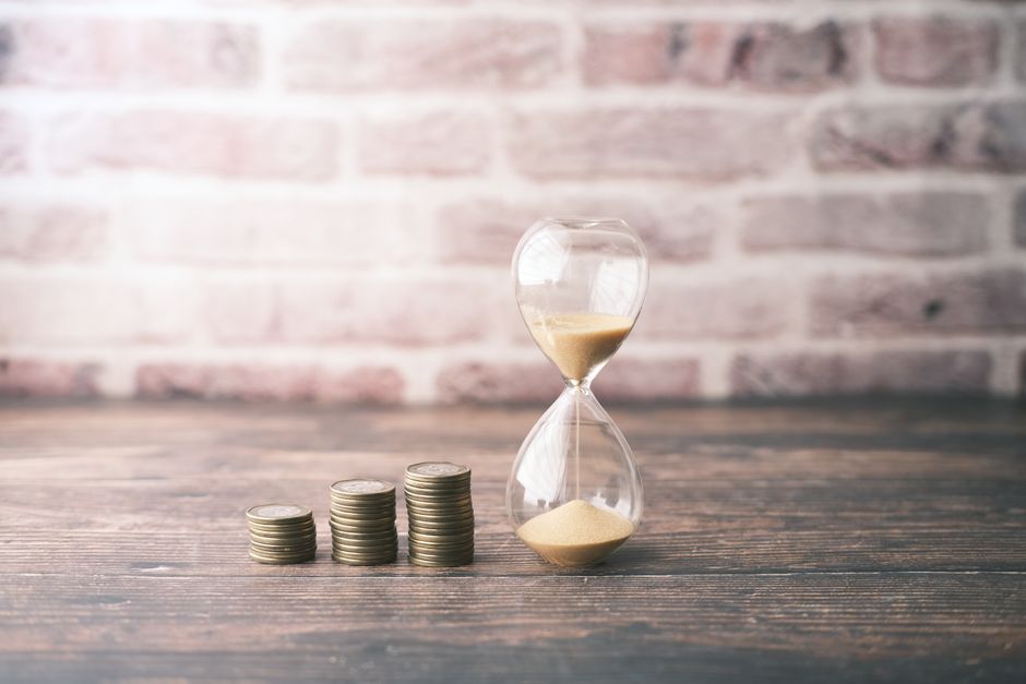Hourglass beside stacked coins, representing the daily cost of holding a property