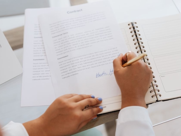 Hands signing a contract on a desk, representing loan documentation