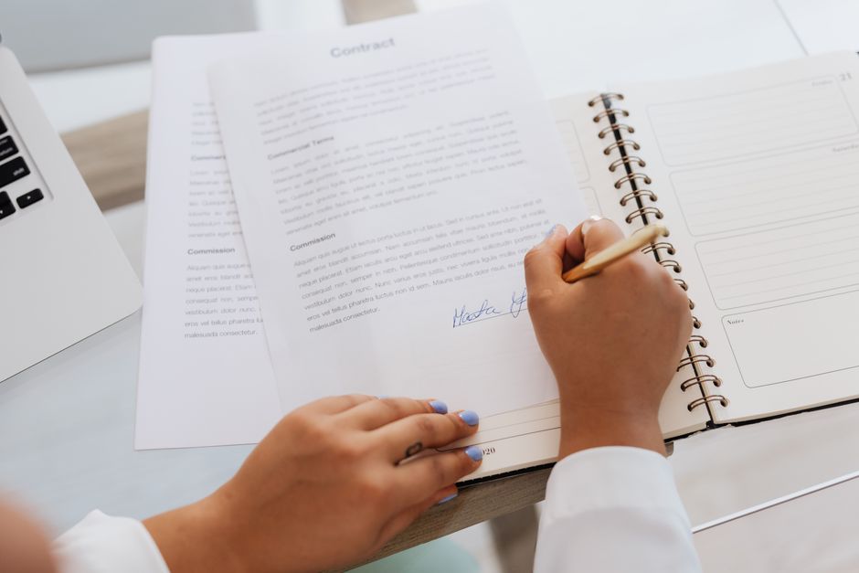 Hands signing a contract on a desk, representing loan documentation